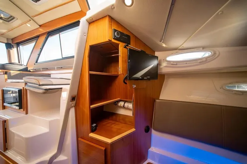 Slide: The Image of 2023 Cutwater C-32 Coupe interior with wood cabinetry, seating, and mounted TV. - 36