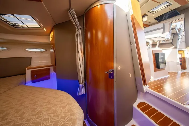 Slide: The Image of 2023 Cutwater C-32 Coupe interior with modern design, wood accents, and cozy sleeping area. - 37