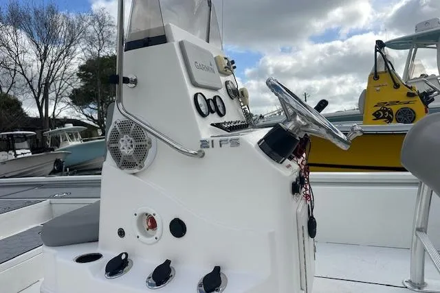 Slide: The Image of Avid 21 Mag 2021 boat console with steering wheel and controls, docked outdoors. - 5