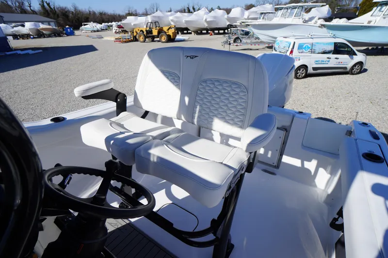 Slide: The Image of 2026 Tidewater 232 CC Adventure boat with white seating and steering wheel in a marina. - 35