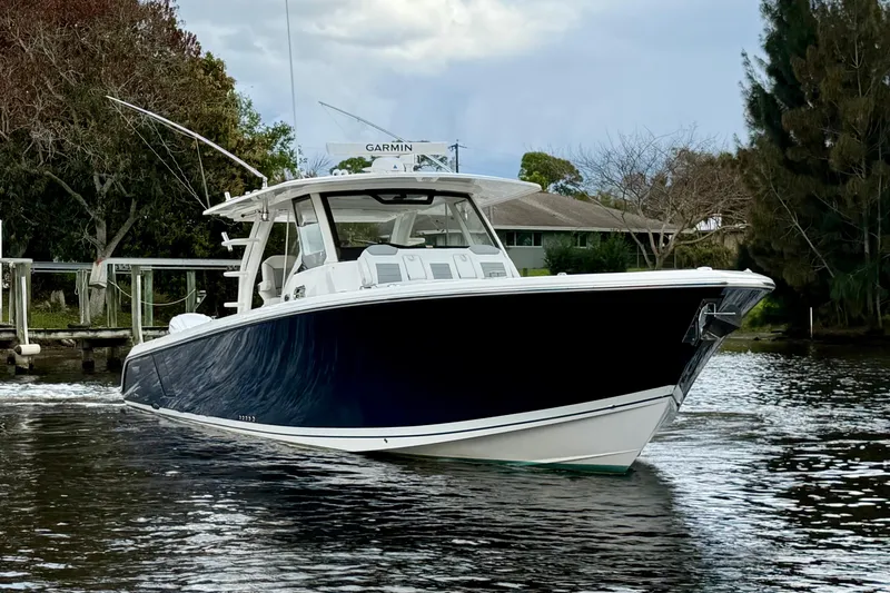 The Image of 2020 Pursuit S 408 Sport boat on calm water, surrounded by trees. - 0