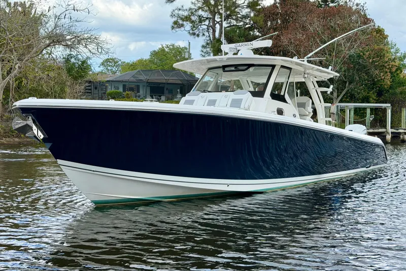 Slide: The Image of 2020 Pursuit S 408 Sport boat on calm water, surrounded by trees. - 3