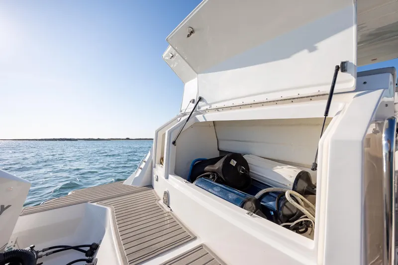 Slide: The Image of 2024 Sea Ray Sundancer 320 Outboard storage compartment with gear, docked on calm water. - 13