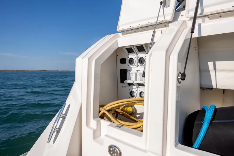 Slide: The Image of 2024 Sea Ray Sundancer 320 Outboard electrical panel with cables, ocean view in background. - 14