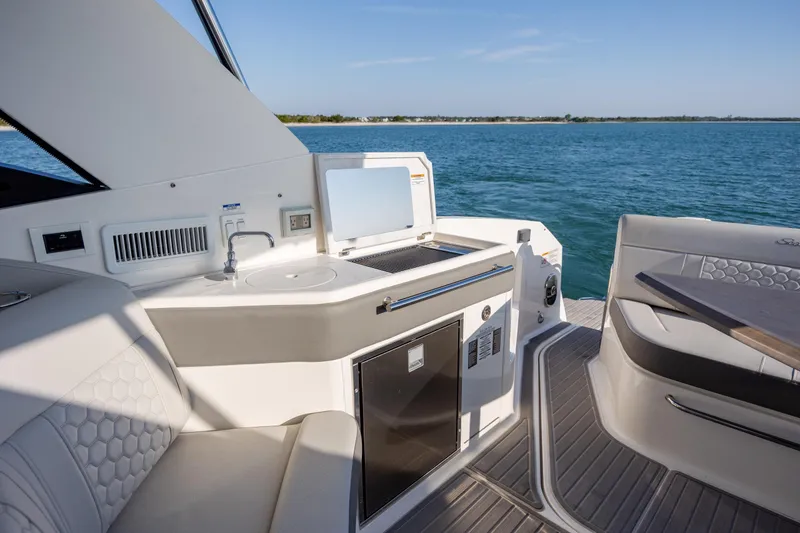 Slide: The Image of Luxurious 2024 Sea Ray Sundancer 320 Outboard boat interior with kitchenette and seating area. - 16