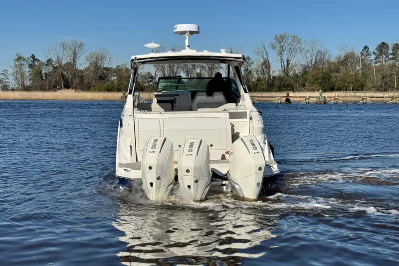 Slide: The Image of 2024 Sea Ray Sundancer 320 Outboard cruising on a calm lake with triple engines. - 5