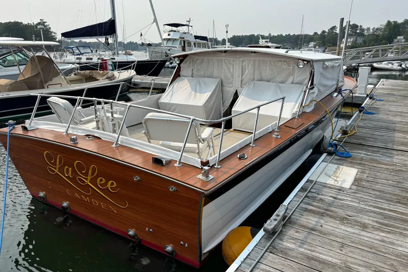 Slide: The Image of 1967 Lyman Islander 30 boat docked, featuring wooden deck and covered seating area. - 12