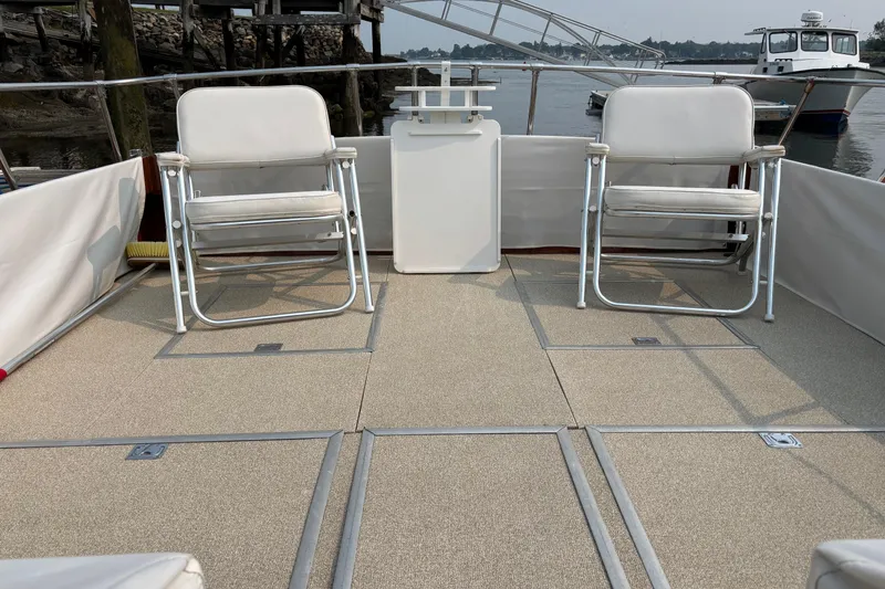 Slide: The Image of 1967 Lyman Islander 30 boat deck with two white chairs, docked by the water. - 13
