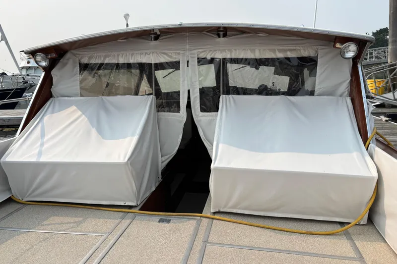 Slide: The Image of 1967 Lyman Islander 30 boat with covered seating and windows at a marina. - 14