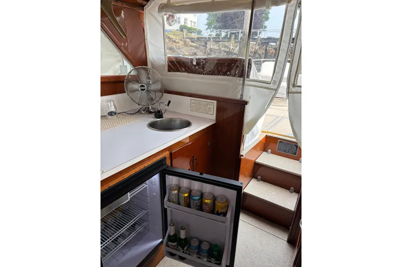 Slide: The Image of 1967 Lyman Islander 30 boat interior with kitchenette, sink, fan, and open mini fridge. - 18