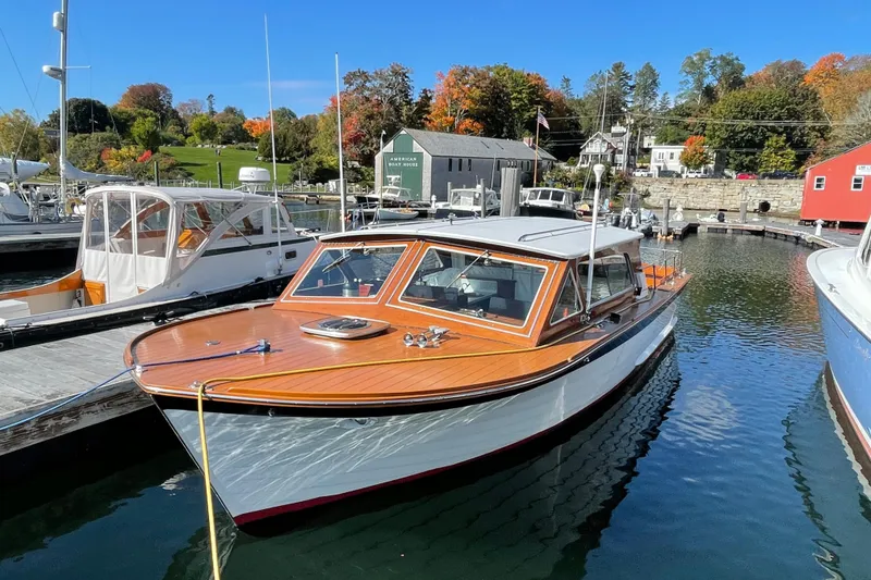 Slide: The Image of 1967 Lyman Islander 30 boat docked in a scenic marina with autumn foliage. - 5