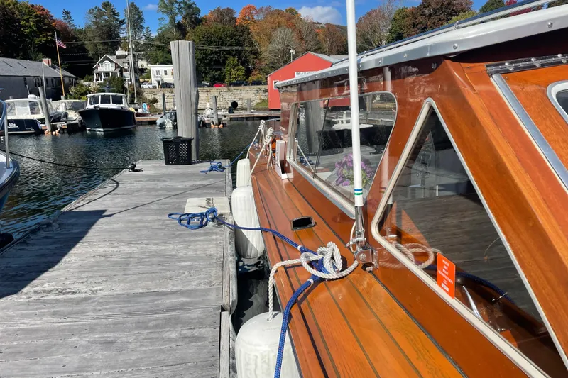 Slide: The Image of 1967 Lyman Islander 30 docked, showcasing polished wooden exterior and marina backdrop. - 7