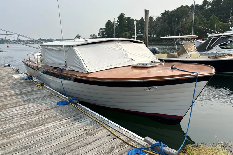 Slide: The Image of 1967 Lyman Islander 30 boat docked, featuring classic wooden design and white canopy. - 8