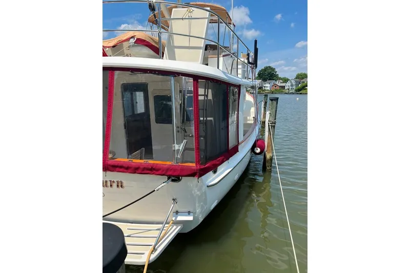 Slide: The Image of 2005 Kadey-Krogen 44 yacht docked on a sunny day, featuring red trim and spacious deck. - 4
