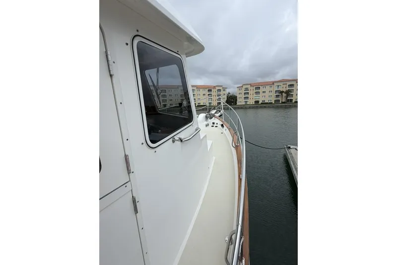 Slide: The Image of 2005 Kadey-Krogen 44 yacht docked near waterfront apartments under cloudy skies. - 9