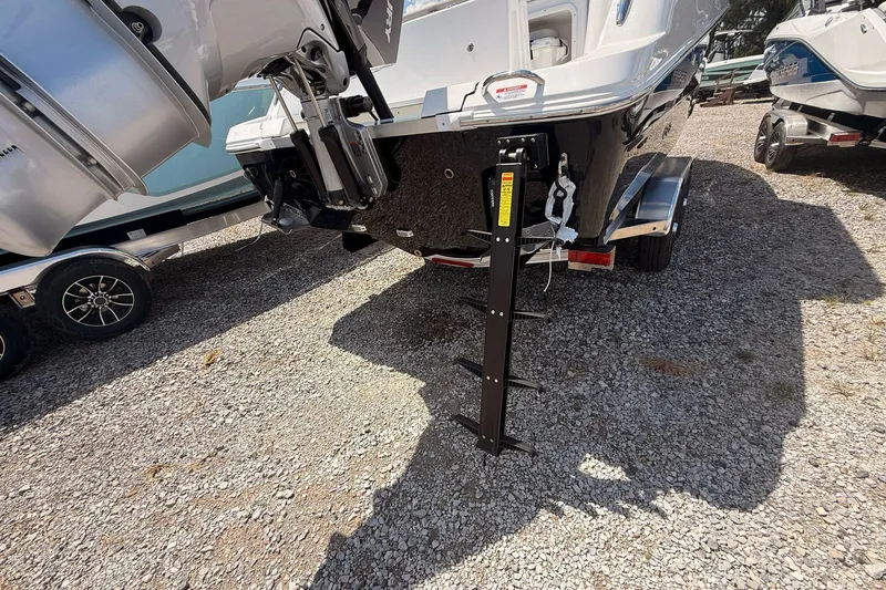 Slide: The Image of 2026 Wellcraft 243 Fisherman boat rear view with motor and trailer on gravel. - 11