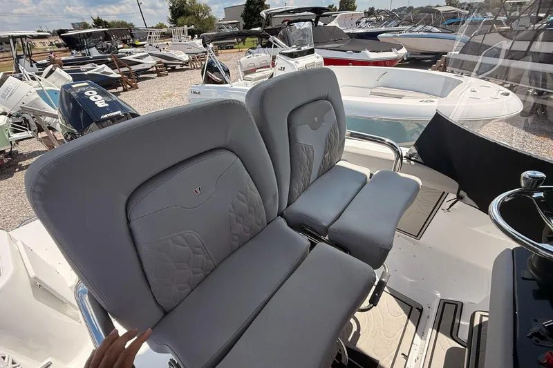 Slide: The Image of 2026 Wellcraft 243 Fisherman boat interior with gray cushioned seating and steering wheel. - 18