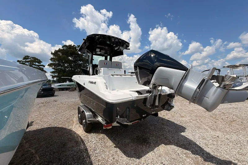 Slide: The Image of 2026 Wellcraft 243 Fisherman boat with powerful outboard motor, parked on gravel under blue sky. - 3