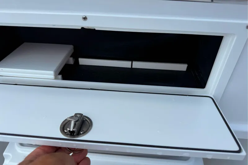 Slide: The Image of Storage compartment on a 2026 Wellcraft 243 Fisherman boat, featuring a secure latch. - 40