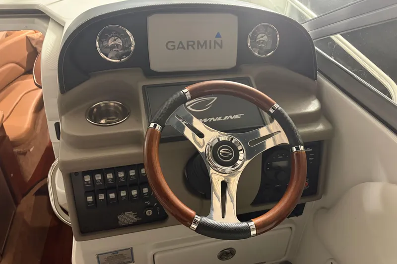Slide: The Image of 2021 Crownline 264 CR boat dashboard with Garmin display and wooden steering wheel. - 15