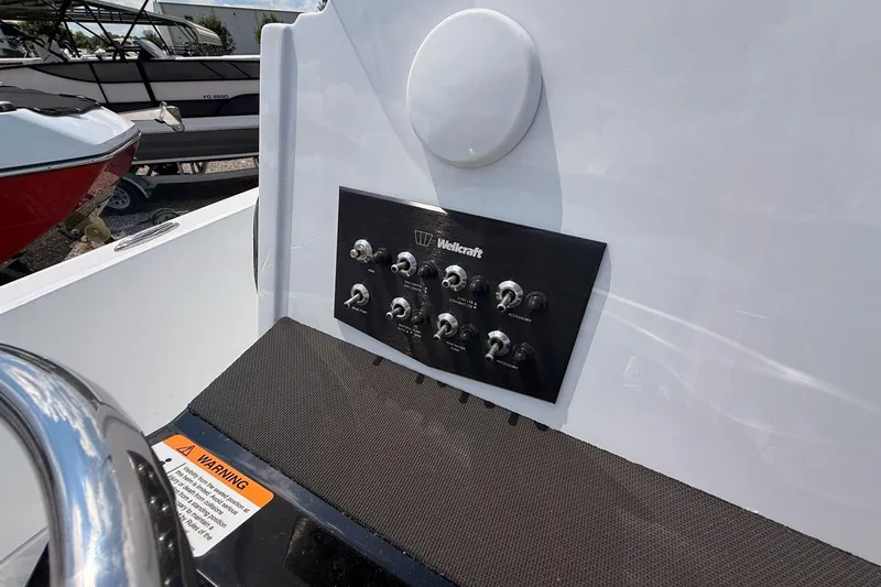 Slide: The Image of Control panel of 2026 Wellcraft 202 Fisherman boat with switches and warning label. - 13