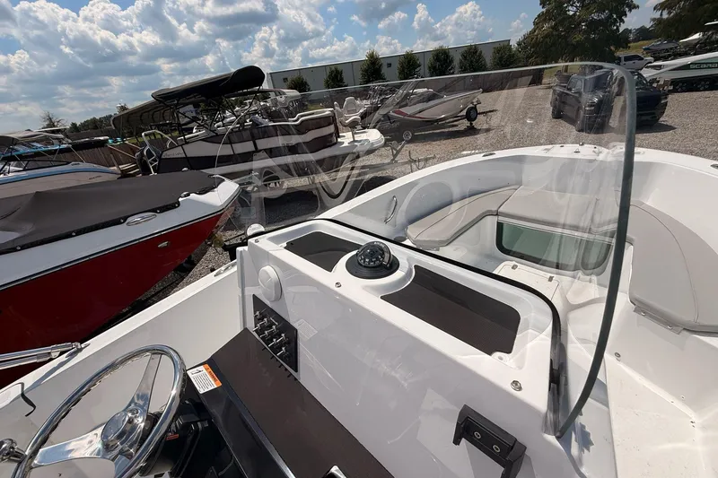 Slide: The Image of 2026 Wellcraft 202 Fisherman boat interior with steering wheel and seating, parked outdoors. - 14