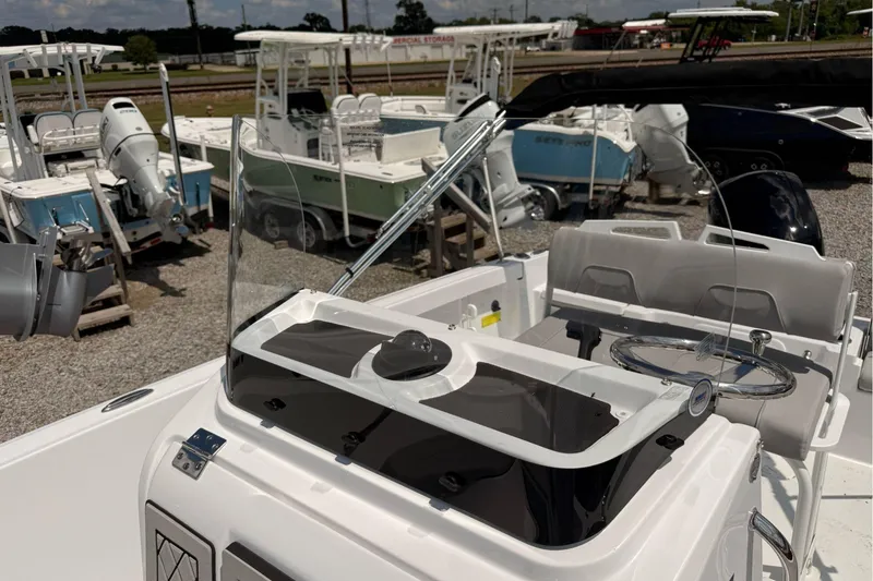 Slide: The Image of 2026 Wellcraft 202 Fisherman boat interior with steering wheel and seating, displayed outdoors. - 24