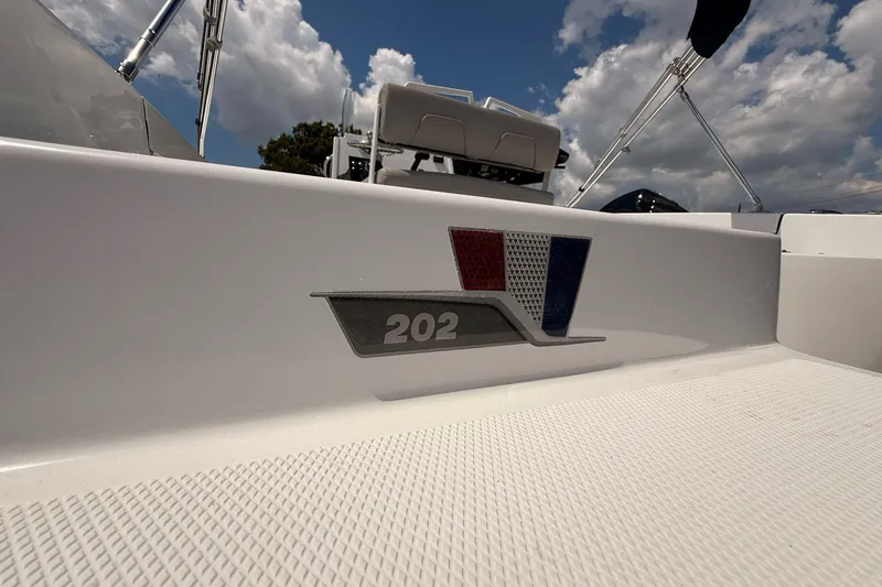 Slide: The Image of 2026 Wellcraft 202 Fisherman boat detail with logo under a cloudy sky. - 6
