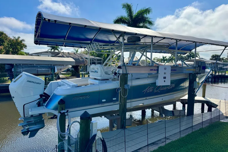 The Image of 2025 Intrepid 327 Cuddy boat docked with Mercury engine, under a canopy, near waterfront. - 1