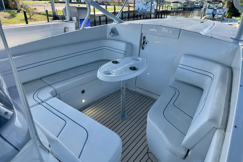 Slide: The Image of 2025 Intrepid 327 Cuddy boat interior with seating and table, docked by a canal. - 19