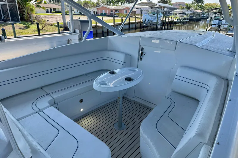 Slide: The Image of 2025 Intrepid 327 Cuddy boat interior with seating and table, docked in a marina. - 23