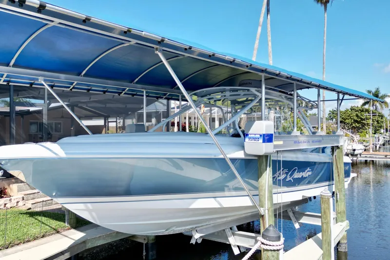 Slide: The Image of 2025 Intrepid 327 Cuddy boat docked under a blue canopy in a marina. - 35