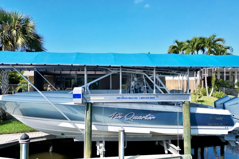 Slide: The Image of 2025 Intrepid 327 Cuddy boat docked under blue canopy, surrounded by tropical greenery. - 36