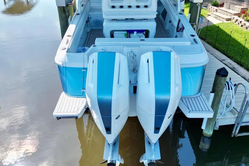 Slide: The Image of 2025 Intrepid 327 Cuddy boat with dual outboard engines docked by the water. - 40