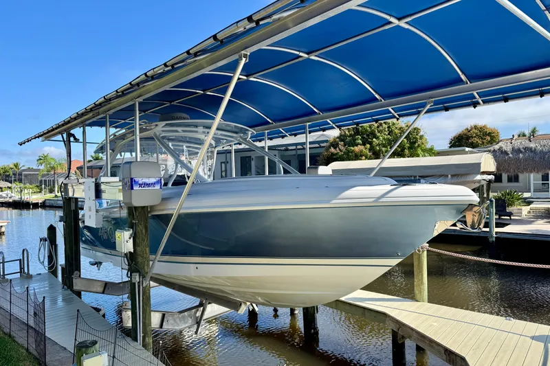 Slide: The Image of 2025 Intrepid 327 Cuddy boat docked under blue canopy in sunny marina. - 5