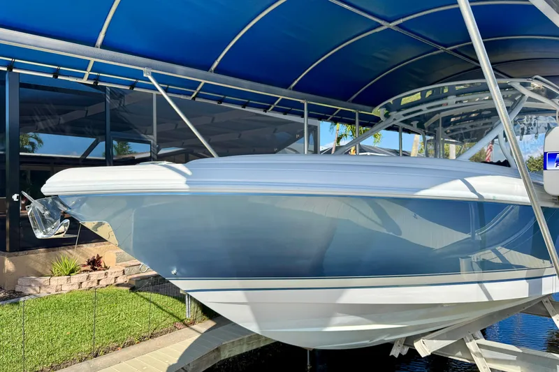 Slide: The Image of 2025 Intrepid 327 Cuddy boat under blue canopy, side view. - 8