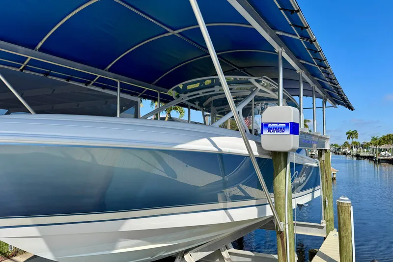 Slide: The Image of 2025 Intrepid 327 Cuddy boat docked under blue canopy by waterfront. - 9
