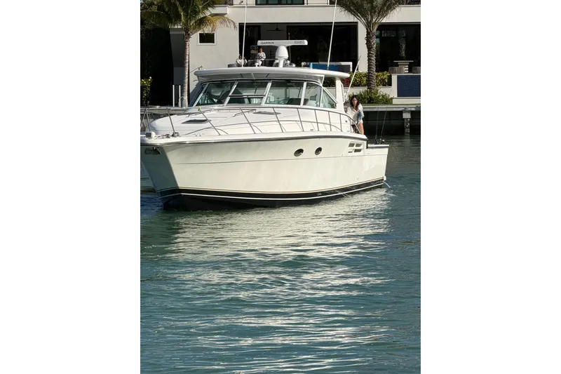 Slide: The Image of 2001 Tiara Yachts 4300 Open cruising on calm waters near a modern building. - 3