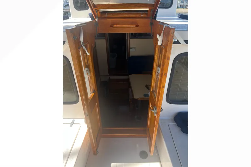 Slide: The Image of Cozy interior of a 1993 Nordic Tug 26 with blue seating and wooden accents. - 26