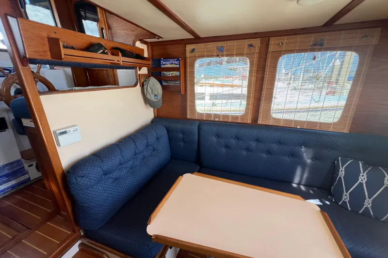 Slide: The Image of Interior of a 1993 Nordic Tug 26, featuring a wooden table and blue cushioned seating. - 27