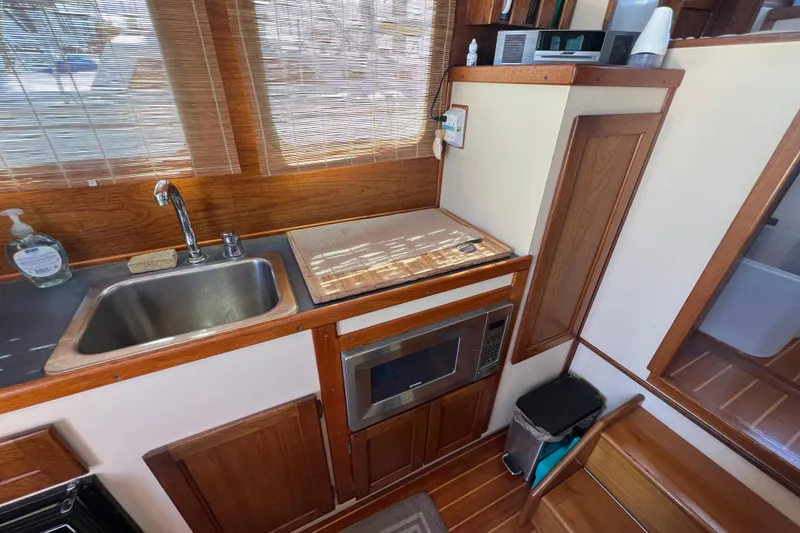 Slide: The Image of 1993 Nordic Tug 26 interior kitchen with stove, microwave, and wooden cabinetry. - 33