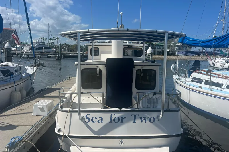 Slide: The Image of 1993 Nordic Tug 26 docked at marina with blue canopy and American flag. - 4