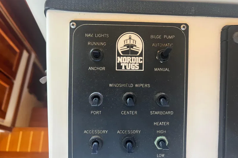 Slide: The Image of Control panel of a 1993 Nordic Tug 26 boat with various switches and gauges. - 44