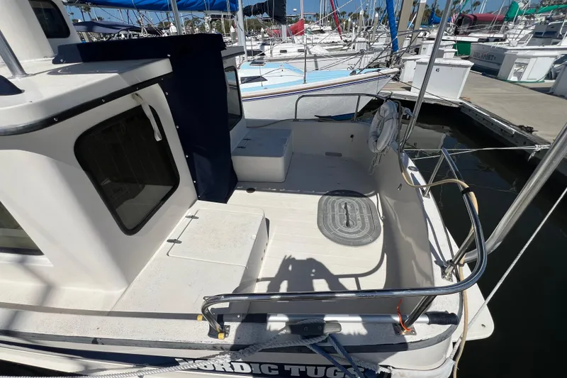 Slide: The Image of 1993 Nordic Tug 26 docked at marina with sailboats in background. - 6