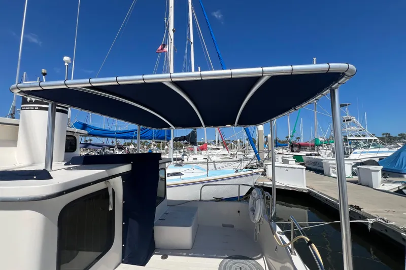 Slide: The Image of 1993 Nordic Tug 26 boat docked, featuring spacious deck and safety railings. - 7