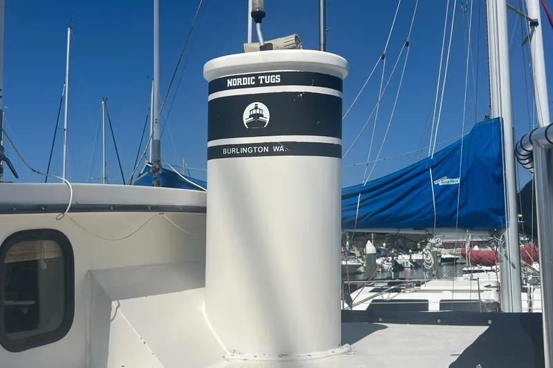 Slide: The Image of 1993 Nordic Tug 26 docked at marina with blue canopy and clear sky. - 8