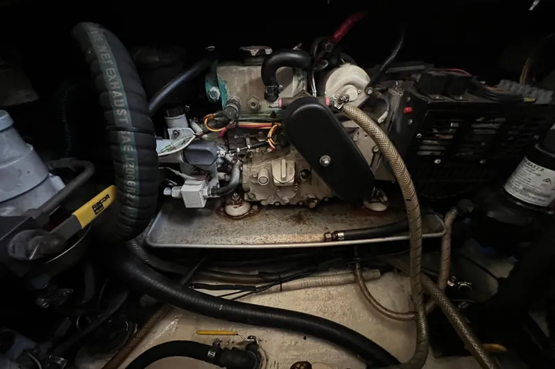 Slide: The Image of Engine components of a 1993 Nordic Tug 26 boat, featuring hoses and metal parts. - 87