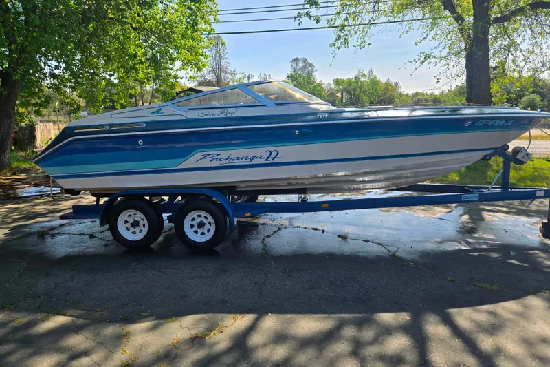 Slide: The Image of 1987 Sea Ray Pachanga 22 boat on trailer, parked outdoors under trees. - 18