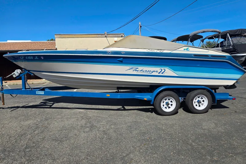 The Image of 1987 Sea Ray Pachanga 22 boat on trailer, blue and white design, parked outdoors. - 9