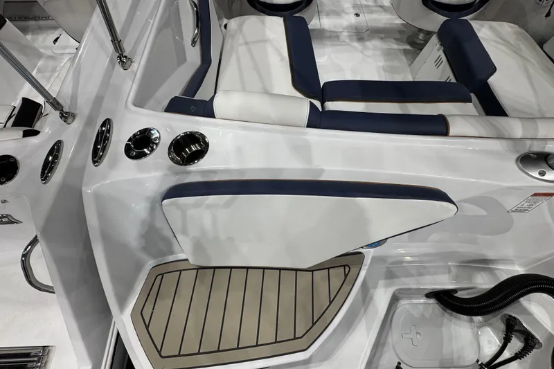 Slide: The Image of 2026 Stingray 20 SBX boat interior with white and navy seating, cup holders, and teak flooring. - 16